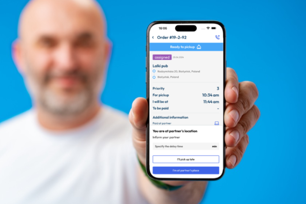 A courier driver holding up a phone interface showing delivery order tracking data